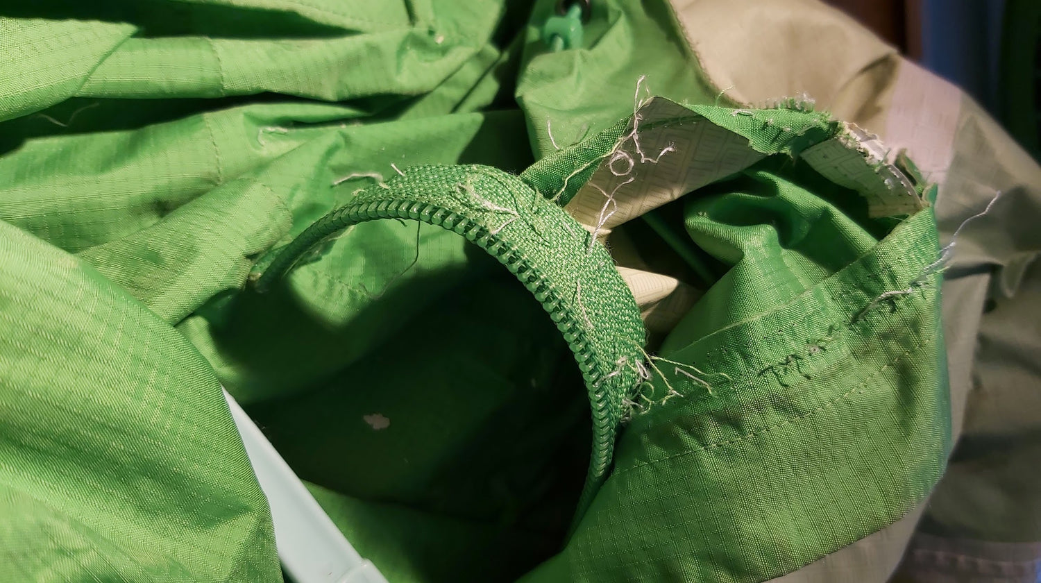 deconstructing the seams of a decommissioned Patagonia hiking jacket for usable fabric zippers and other hardware